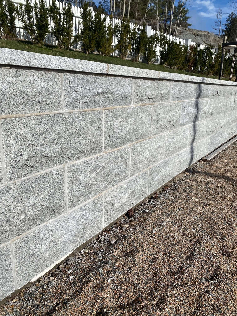 Beklädnadssten i granit. Med fog i murbruk. Grå. stengrossen