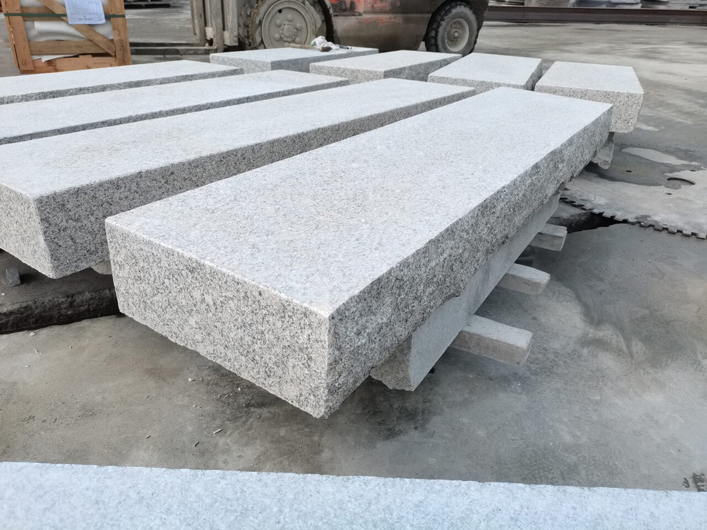 En närbild av trappsteg i granit från Stengrossen visar den naturliga strukturen, slipade stegytan och den råkilade framsidan som ger ett gediget uttryck.