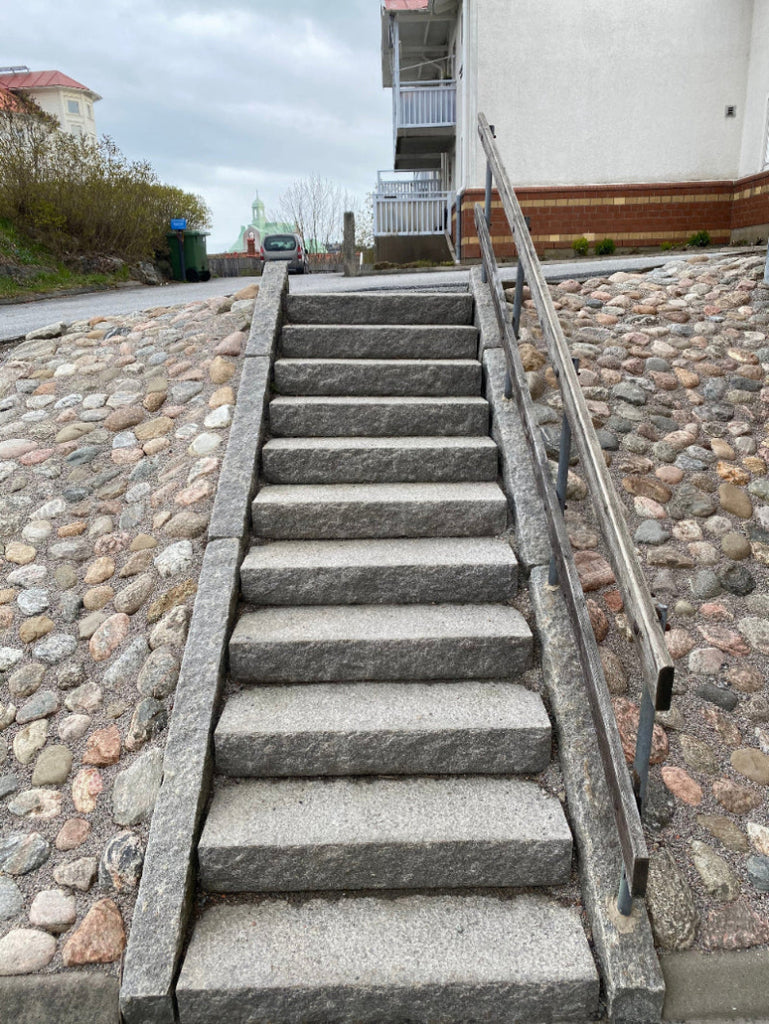 Lång granittrappa med ca 11 steg, inramad av grå Bohuskantsten som fungerar som vangstycken. Stengrossen säljer produkten.