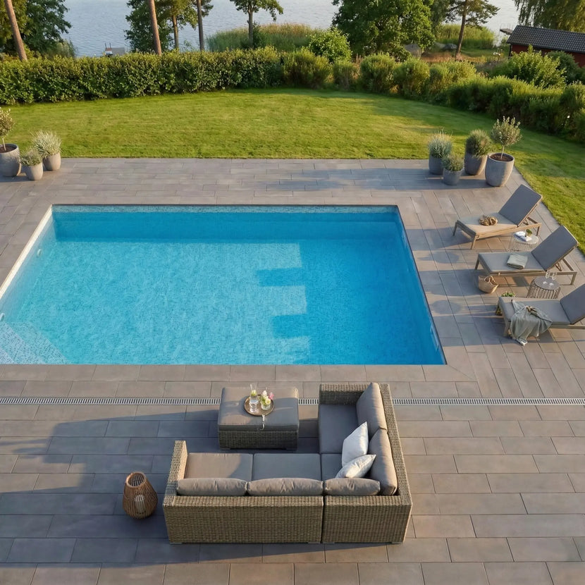 Utomhuspool med granitplattor i grafit 60x30x3 cm, utemöbler och blommor runt om, Stengrossen säljer produkten.
