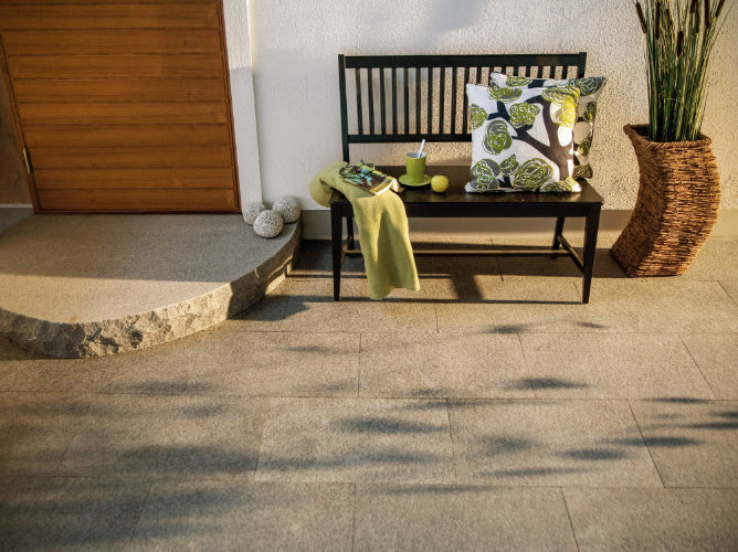 Stenplattor i granit. En dörr med ett entréplan i granit. Ovanpå granitplattorna står det en soffa i svart trä. Öven en kruka i rotting står ovanpå plattorna. Säljs av Stengrossen.se