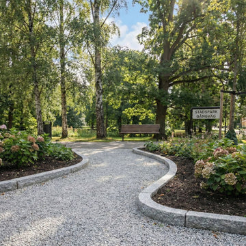 Kantsten i granit som ramar in blomsterbäddar i en park. Kantstenarna är båda raka och böjda (radiesten). Mellan kantstenarna ligger det gårdsgrus. Stengrossen säljer kantstenar och gårdsgrus.