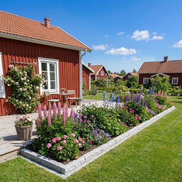 Grå granitkantsten Mini 50x15x7,5 cm som ramar in en blomsterbädd fylld med svenska sommarblommor framför ett rött hus med altan på sidan. Stengrossen säljer produkten.