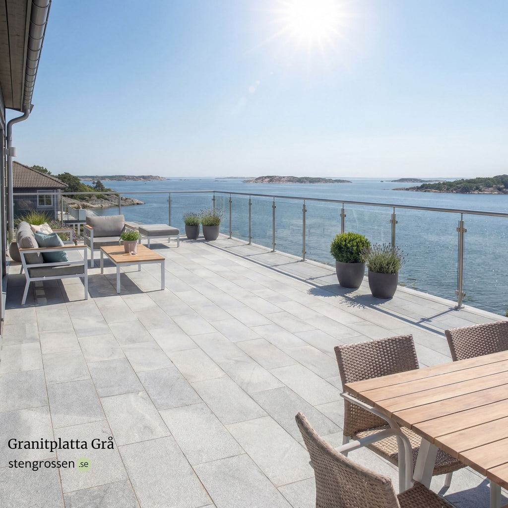 Grå granitplatta 60x30x3 cm lagd på solig altan vid skärgårdshus, omgiven av moderna utemöbler, blommor och glasräcke; Stengrossen säljer produkten.