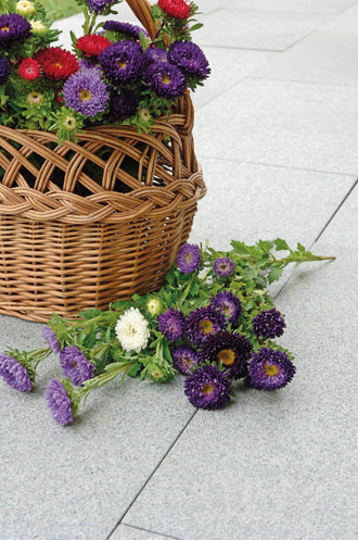 Hällar i granit. Ovanpå de dessa hällar står det en korg med blommor. Det ligger även snittblommor ovanpå hällarna. Säljs av Stengrossen.se