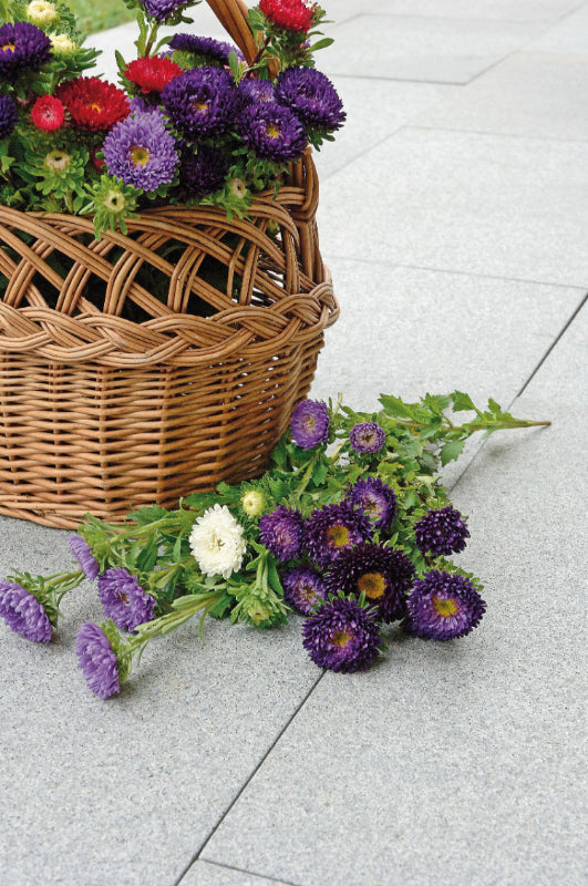 Hällar i granit. Ovanpå de dessa hällar står det en korg med blommor. Det ligger även snittblommor ovanpå hällarna. Säljs av Stengrossen.se