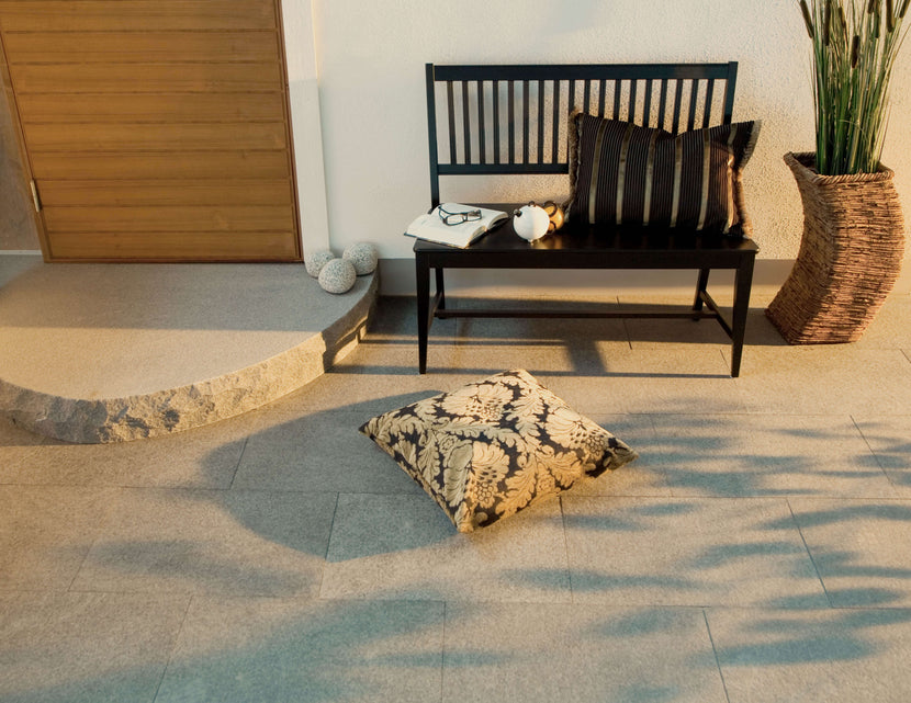 Plattor av granit. Ligger framför ett hs med en trädörr. Framför dörren ligger det ett entréplan i granit. Ovanpå plattorna står det en kruka samt en soffa i svart trä. Säljs av Stengrossen.se