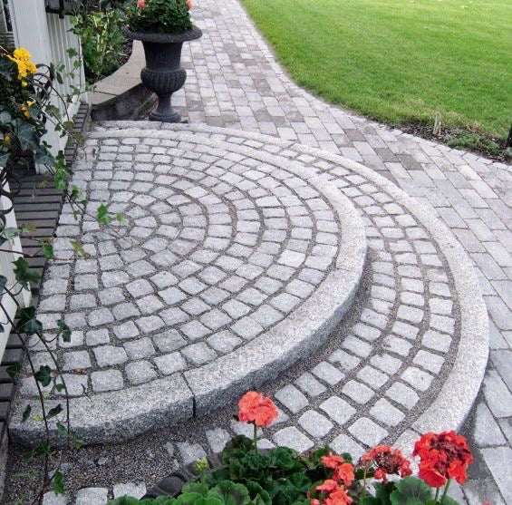 En trappa som är byggd av kantstenar med radie. Trappan är lagd med smågatsten mellan radiekantstenarna. Produkterna säljs av Stengrossen.