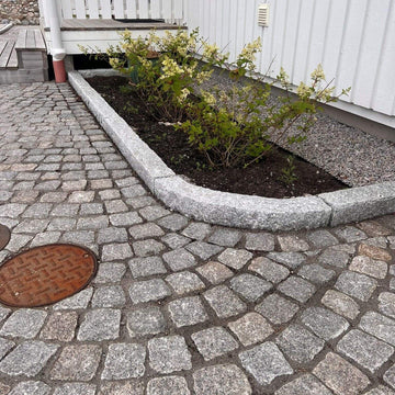 Granitkantsten GV4 i färgen grå, med måtten 100x25x10 cm. Vid denna stensättning finns även radiestenar i kantstenen, och på nedsidan av kantstenen ligger smågatsten. På ovansidan av kantstenen finns en bädd med planteringar. Stengrossen säljer produkten.