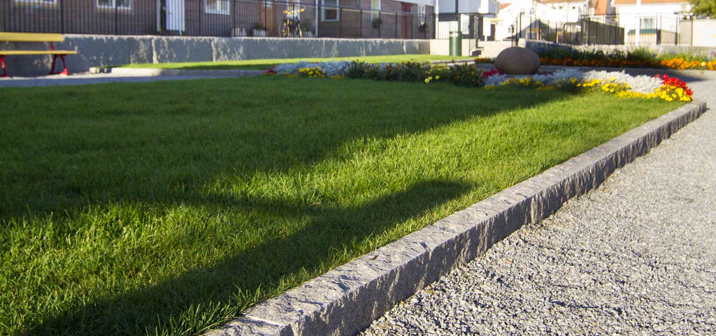 Elegant granitkantsten, perfekt för att avgränsa trädgårdsytor. Kantstenen separerar grus från gräsmatta med planteringar med blommor. Säljs av Stengrossen.se