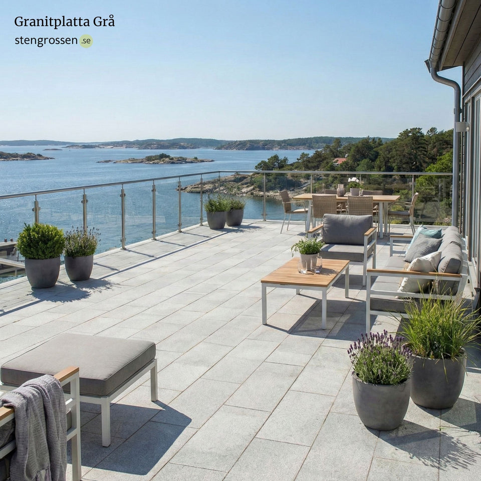 Altan vid skärgården med solig miljö, grå granitplatta 60x30x3 cm, moderna möbler, blommor och glasräcke runt uteplatsen; Stengrossen säljer produkten.