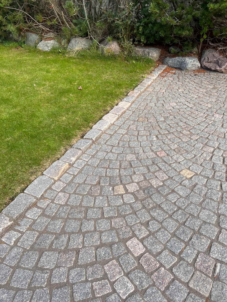 Storgatsten som kant mot gräsmatta. På insidan är det smågatsten. Graniten är svensktillverkad Bohusgranit. Fogen är en hårdfog från tillverkaren PCI. Fogen är en hårdfog som är dränerande och heter Pavifix 1K Extra. Säljs av Stengrossen.se 