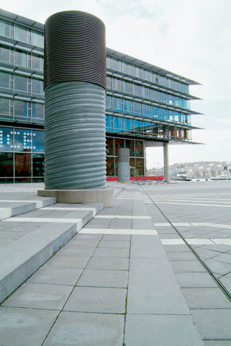 Grå Superplattan använd på ett modernt torg, där den täta betongen och exakta formen ger en harmonisk och slitstark beläggning. Stengrossen säljer produkten. Tillverkad av S:T Eriks