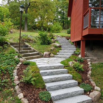 Grå granittrappsteg från Stengrossen i en slänt som formar en svängd trappa.