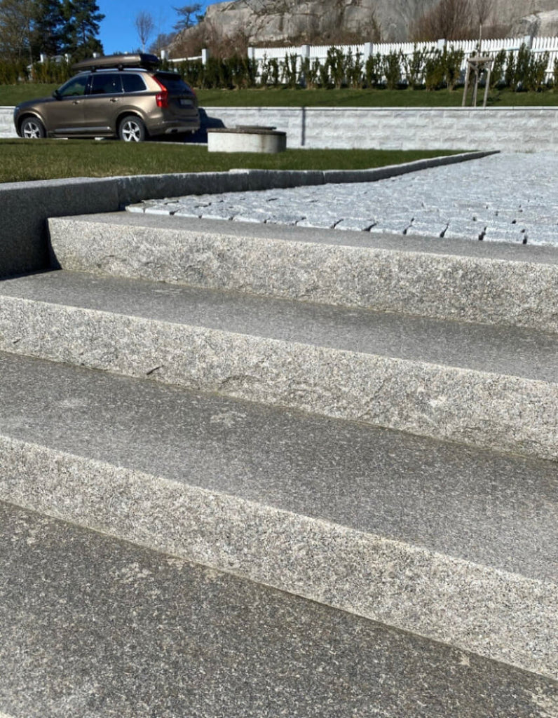 Blocksteg i Bohuslänsgranit med rustik råkilad framkant och flammad toppyta. Passar utmärkt för utomhustrappor. Stengrossen säljer produkten.
