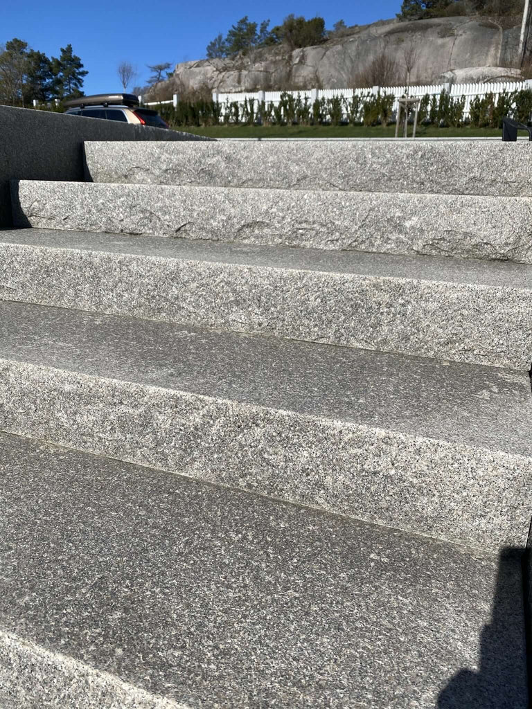 Grå Bohusgranit i närbild, visar blocksteg med råkilad front och halksäker flammad ovansida. Stengrossen säljer produkten.