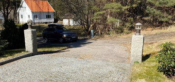 Två grå granitstolpar i Bohusgranit som ramar in en infart till ett hus. Stengrossen säljer produkten.