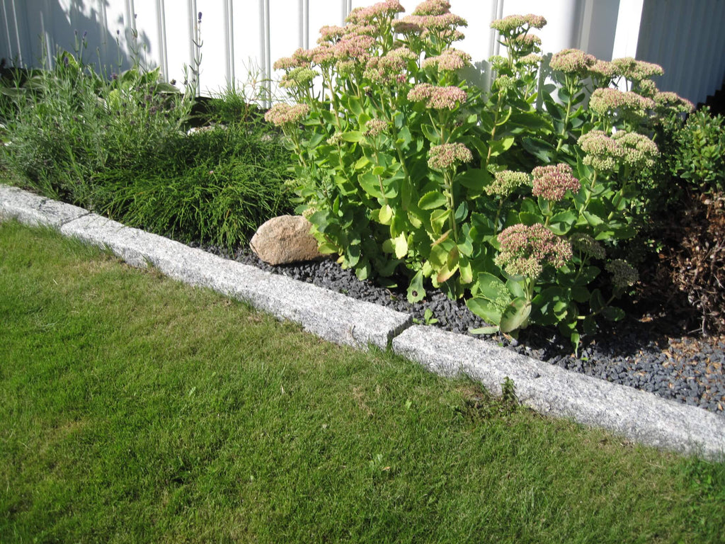 Grå granitkantsten 50x15x7,5 cm – Skapar en snygg avgränsning mellan gräsmatta och dekorsten i grafitfärgad diabas. Säljs av Stengrossen.