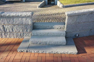Blocksteg i Grå Bohus, en granit från Bohuslän, med flammad ovansida och råkilade kanter för en stilren och stabil trappa. Stengrossen säljer produkten.