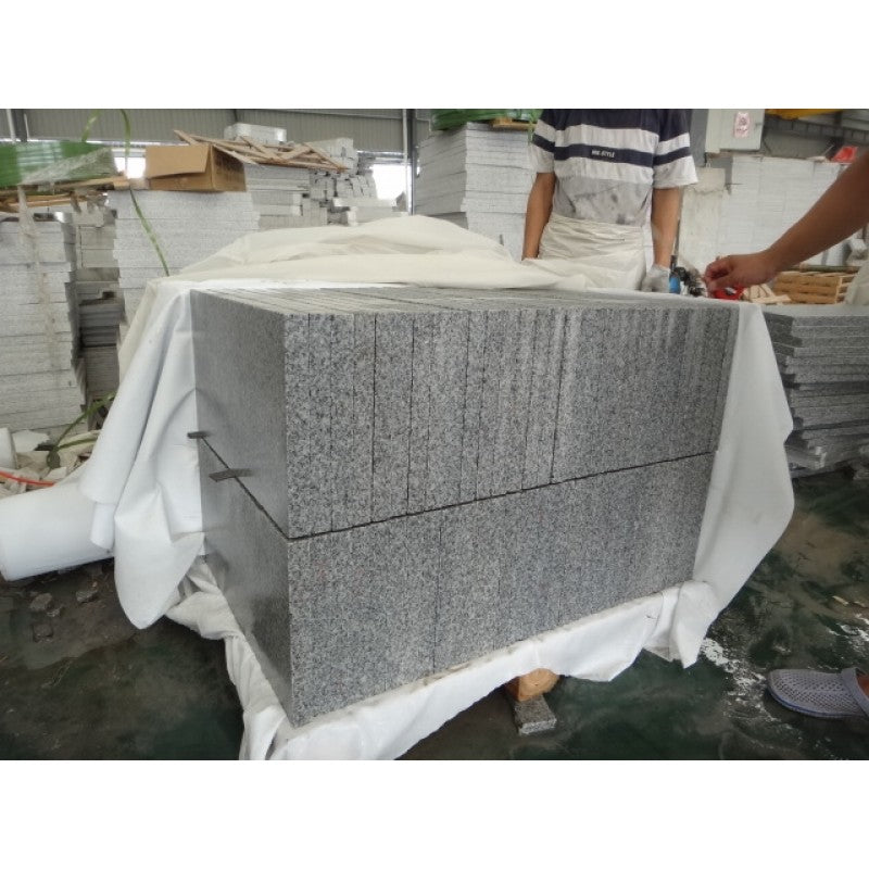 Bild som visar hur vi packar våra granitplattor i fabriken. Här är det två lager ovanpå en träpall. Färgen är grå. Storleken är 60x30x3 cm på plattorna. Säljs av Stengrossen.