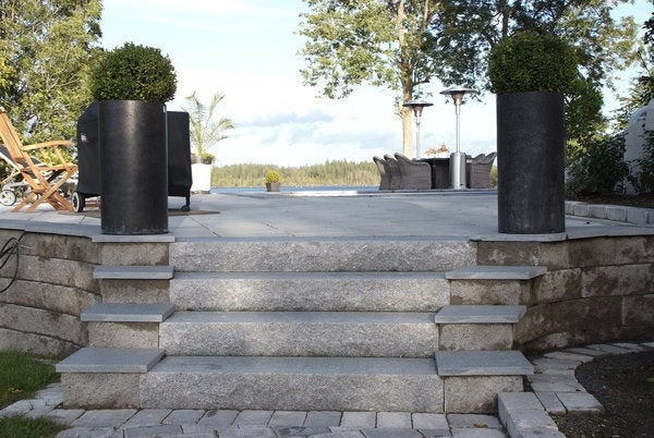 En stilren trappa med fyra blocksteg i granit från Stengrossen leder upp till en inbjudande uteplats. Omgärdad av gedigna murar skapar den en harmonisk och exklusiv entré.