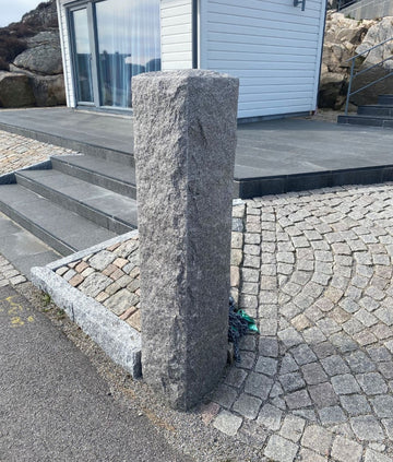 Gedigen grå granitstolpe med naturlig struktur, perfekt för stabil montering. Stengrossen säljer produkten.
