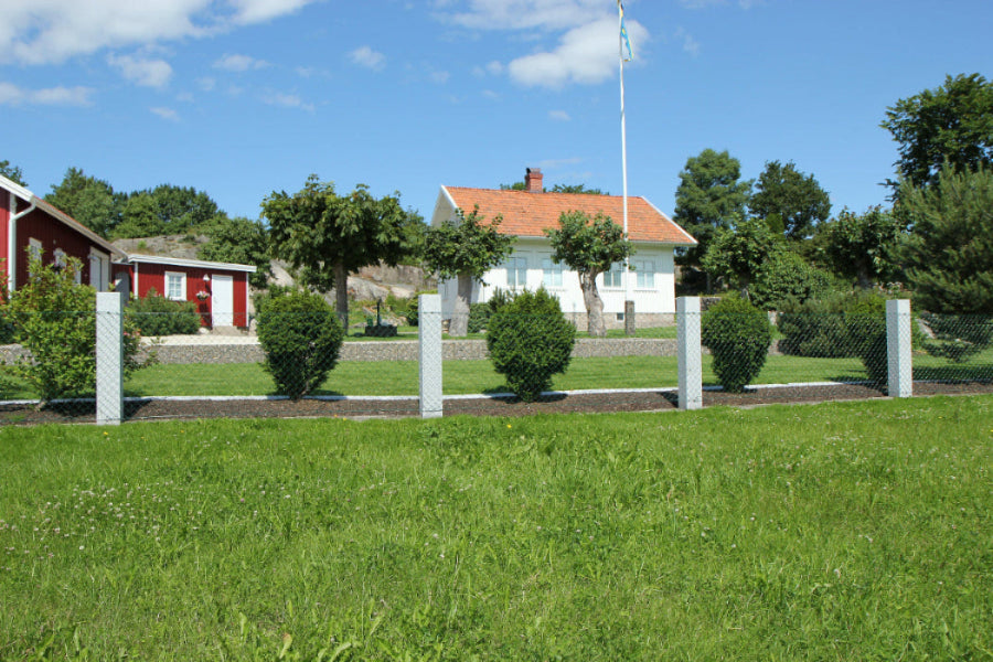 Tidlösa flammade granitstolpar som avgränsar en vacker trädgård. Stengrossen säljer produkten.