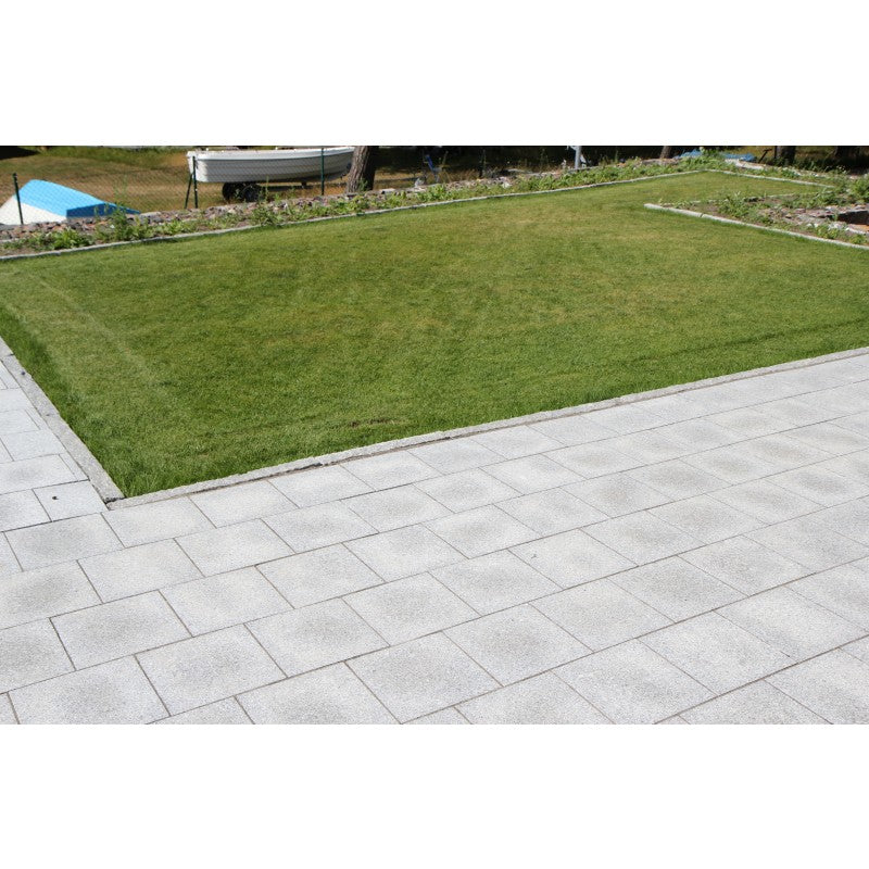 Granithäll framför en gräsmatta. Storleken på hällarna är 30x30x3 cm. Färgen är grå. Stensorten är G603. Mellan hällarna och gräsmattan finns det kantsten i granit. Säljs av Stengrossen.se
